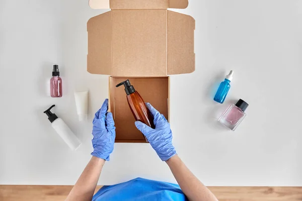 Mains dans des gants emballage boîte de colis avec des cosmétiques — Photo