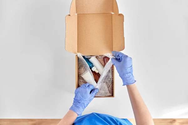 Händer i handskar förpackning paket låda med kosmetika — Stockfoto