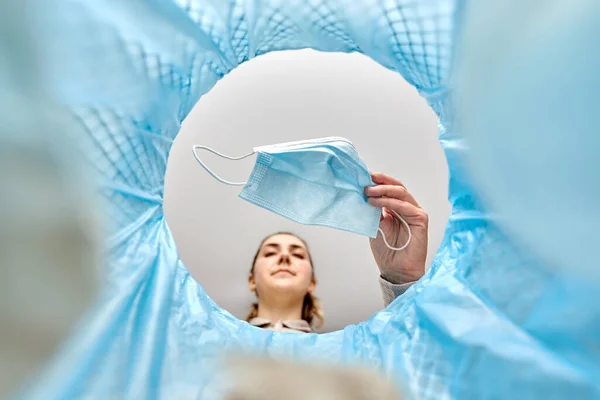 Mujer arrojando máscara médica usada en bote de basura — Foto de Stock