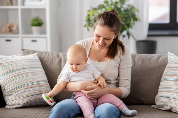 Anne ve küçük bebek evde çıngırakla oynuyorlar. — Stok fotoğraf