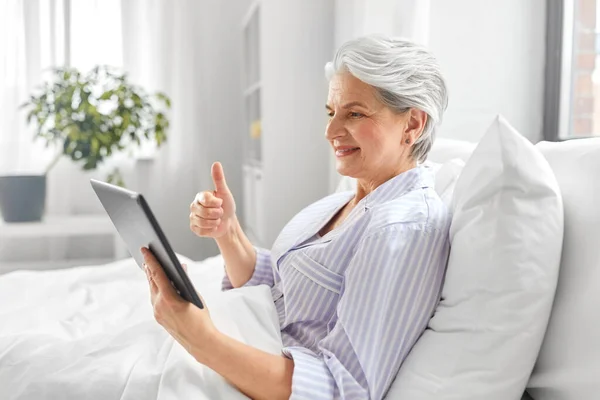 Mulher velha com tablet pc ter chamada de vídeo na cama — Fotografia de Stock