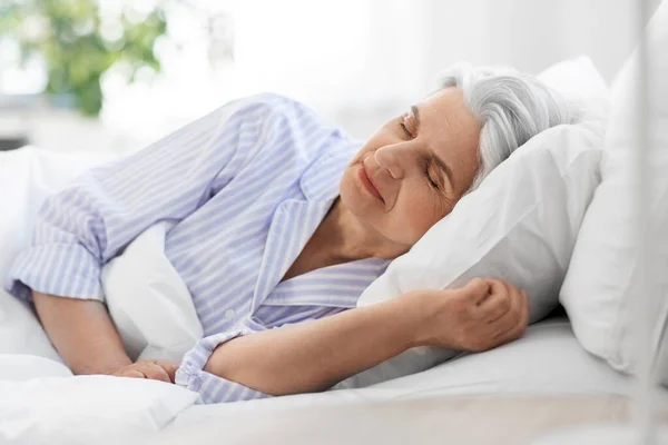 Wanita senior tidur di ranjang di kamar tidur rumah — Stok Foto