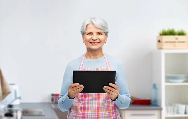 Усміхнена старша жінка з планшетним ПК на кухні — стокове фото