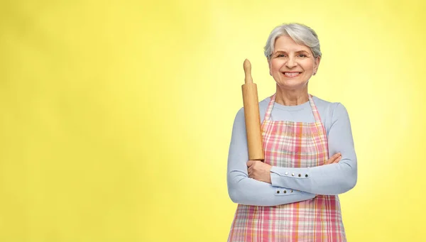 Glimlachende senior vrouw in schort met rollende pin — Stockfoto