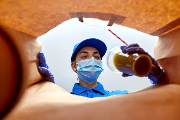 Delivery girl in gloves and mask with food in bag — Stock Photo, Image