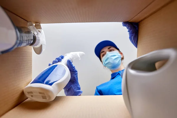 Femme dans le masque emballage nettoyage fournitures dans la boîte — Photo