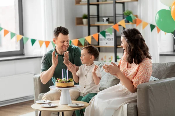 Família feliz com bolo de aniversário em casa — Fotografia de Stock