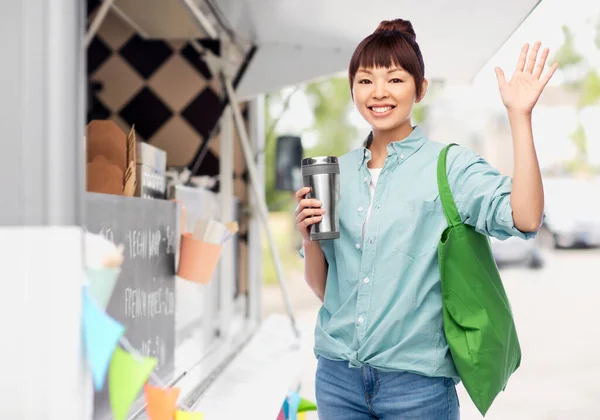 Woman with tumbler and bag over food truck — Stock Photo, Image