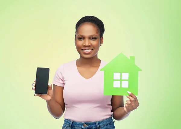 Mulher africana com smartphone e casa verde — Fotografia de Stock