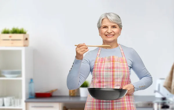 Glimlachende senior vrouw met koekenpan in de keuken — Stockfoto