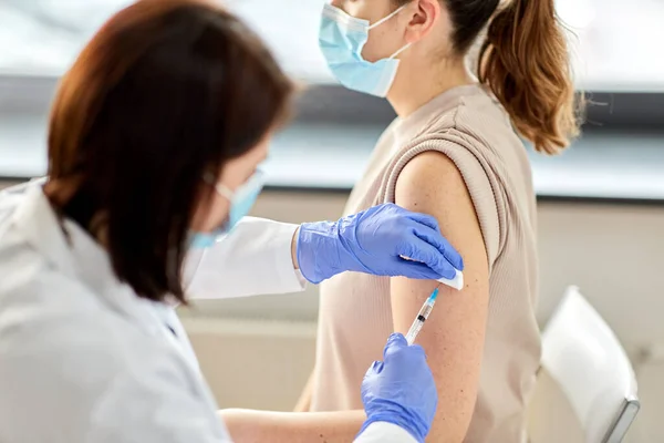 Vrouwelijke arts met injectiespuit vaccinerende patiënt — Stockfoto