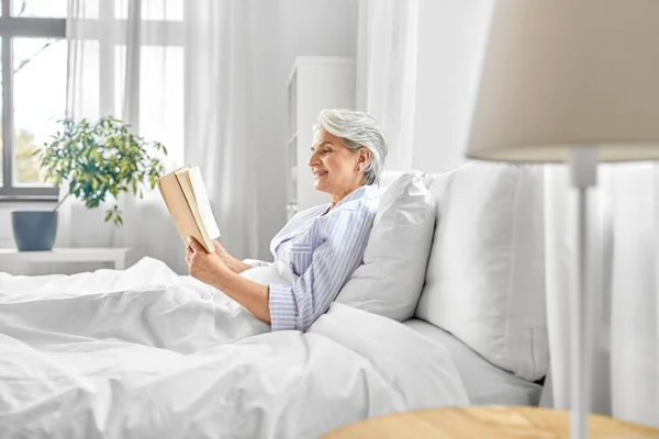 Son sınıf öğrencisi kadın yatak odasında kitap okuyor. — Stok fotoğraf