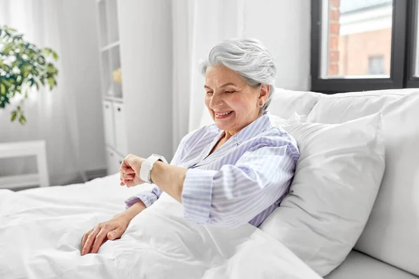 Felice donna anziana seduta a letto a casa camera da letto — Foto Stock