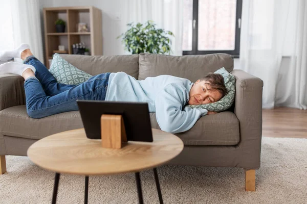 Homme ennuyé avec tablette PC couché sur le canapé à la maison — Photo