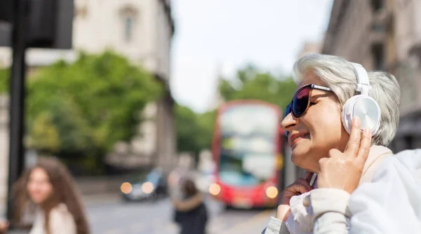 Vieille femme dans casque écoute de la musique à Londres — Photo