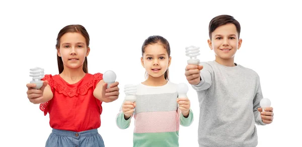 Smiling children comparing different light bulbs — Stock Photo, Image