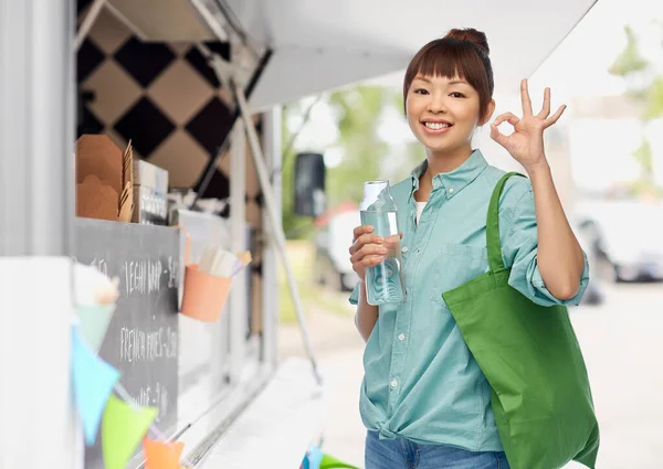 Vrouw met boodschappentas en fles over food truck — Stockfoto