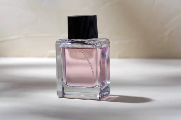 Láhev parfému na bílém povrchu se stíny — Stock fotografie