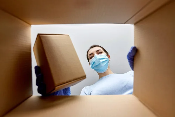 Mujer en máscara tomando caja de paquete —  Fotos de Stock