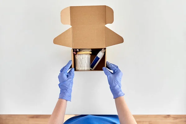 Händer i handskar förpackning paket låda med kosmetika — Stockfoto