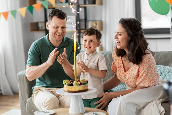 Família feliz com bolo de aniversário em casa — Fotografia de Stock