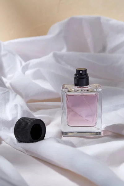 Lahvička parfému a uzávěr na bílém prostěradle — Stock fotografie