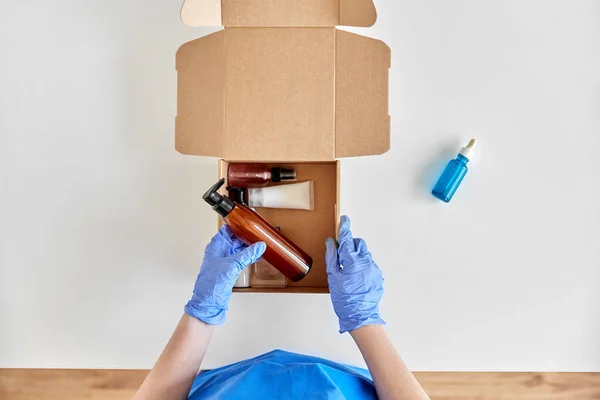 Mains dans des gants emballage boîte de colis avec des cosmétiques — Photo