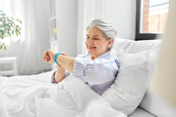 Feliz anciana con rastreador de salud sentada en la cama — Foto de Stock