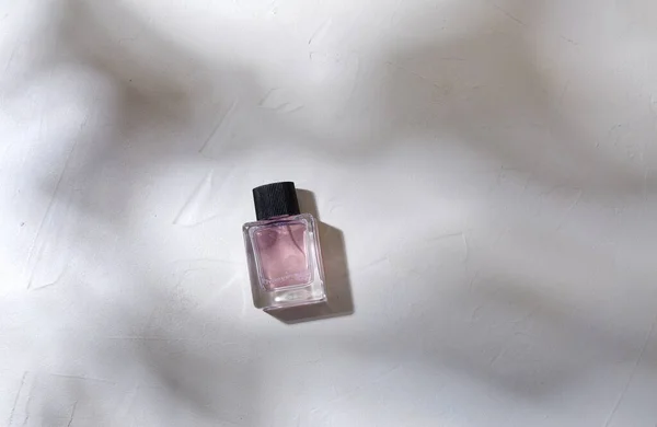 Garrafa de perfume na superfície branca com sombras — Fotografia de Stock