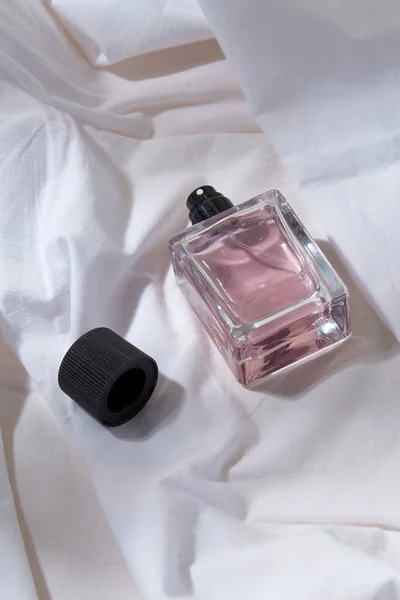 Bottle of perfume and cap on white sheet — Stock Photo, Image