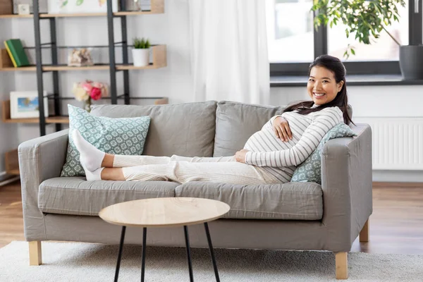 Feliz embarazada asiático mujer sentado en sofá en casa —  Fotos de Stock