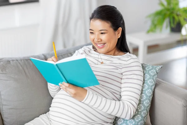 Heureuse femme enceinte écrit à journal intime à la maison — Photo