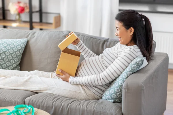 Счастливая беременная женщина открывает подарочную коробку дома — стоковое фото