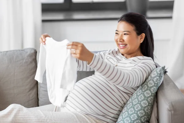 Femme enceinte heureuse avec costume de bébé à la maison — Photo