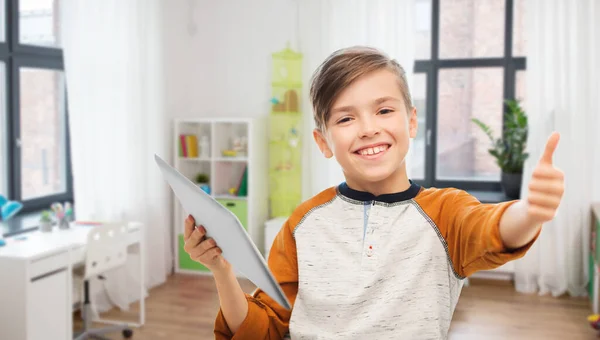 Tabletli gülümseyen çocuk evde baş parmağını gösteriyor. — Stok fotoğraf