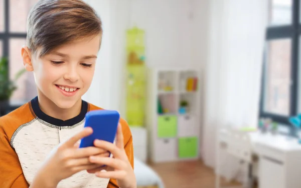 Menino com mensagens de texto smartphone ou jogar em casa — Fotografia de Stock