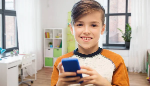 Мальчик со смартфоном смс или играть дома — стоковое фото