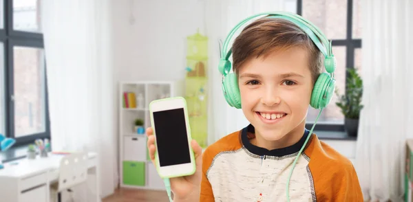 Glad pojke med smartphone och hörlurar hemma — Stockfoto