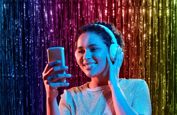Kobieta w słuchawkach ze smartfonem na imprezie — Zdjęcie stockowe