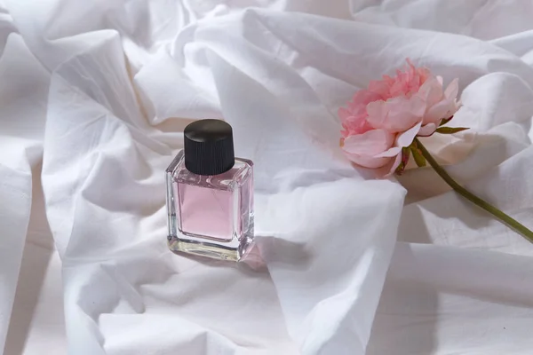 Bottle of perfume and flower on white sheet — Stock Photo, Image