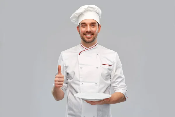 Glücklicher männlicher Koch mit leerem Teller, der Daumen nach oben zeigt — Stockfoto