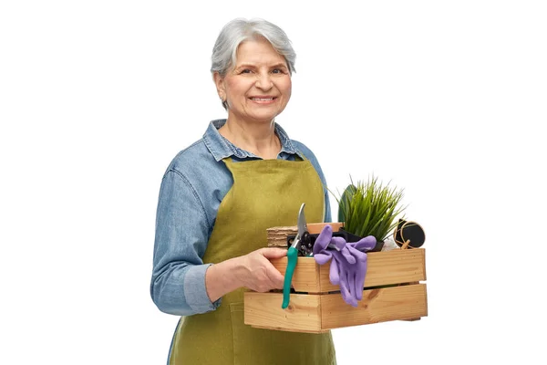 Mulher sênior sorridente com ferramentas de jardim na caixa — Fotografia de Stock