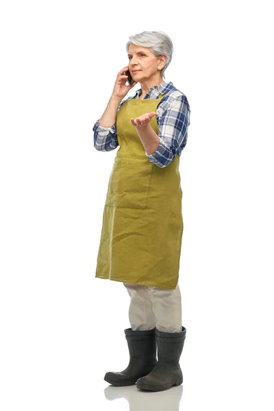 Senior woman in garden apron calling on smartphone — Stock Photo, Image