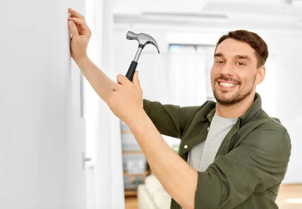 Glimlachende man hameren nagel aan muur thuis — Stockfoto