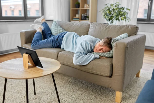 Homme ennuyé avec tablette PC couché sur le canapé à la maison — Photo