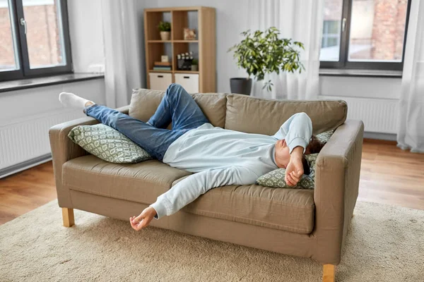 Unatkozik vagy lusta fiatalember feküdt kanapén otthon — Stock Fotó
