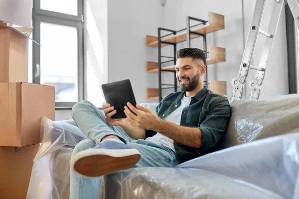 Hombre con la tableta PC y cajas que se mueven en el nuevo hogar —  Fotos de Stock