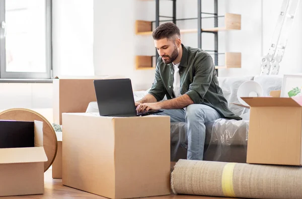 Man with laptop computer and moving into new home — Stock Photo, Image