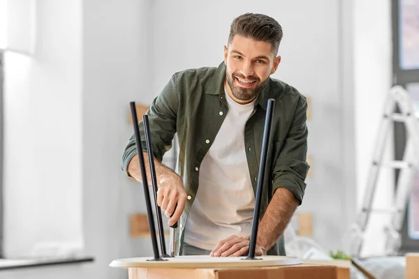 Homem feliz montando mesa de café na nova casa — Fotografia de Stock