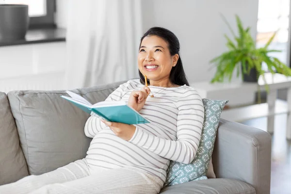 Счастливая беременная пишет дневник на дому — стоковое фото